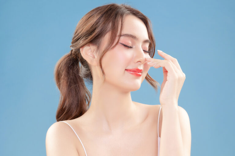Young Asian beauty woman pull back hair with Koreans makeup style on face and perfect clean skin on isolated blue background. Facial treatment, Cosmetology, plastic surgery.